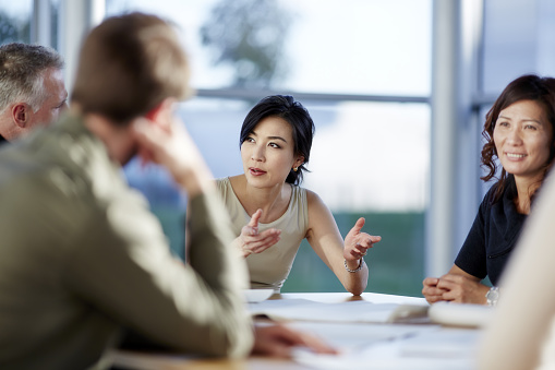 Female Thai executive leads an international meeting.